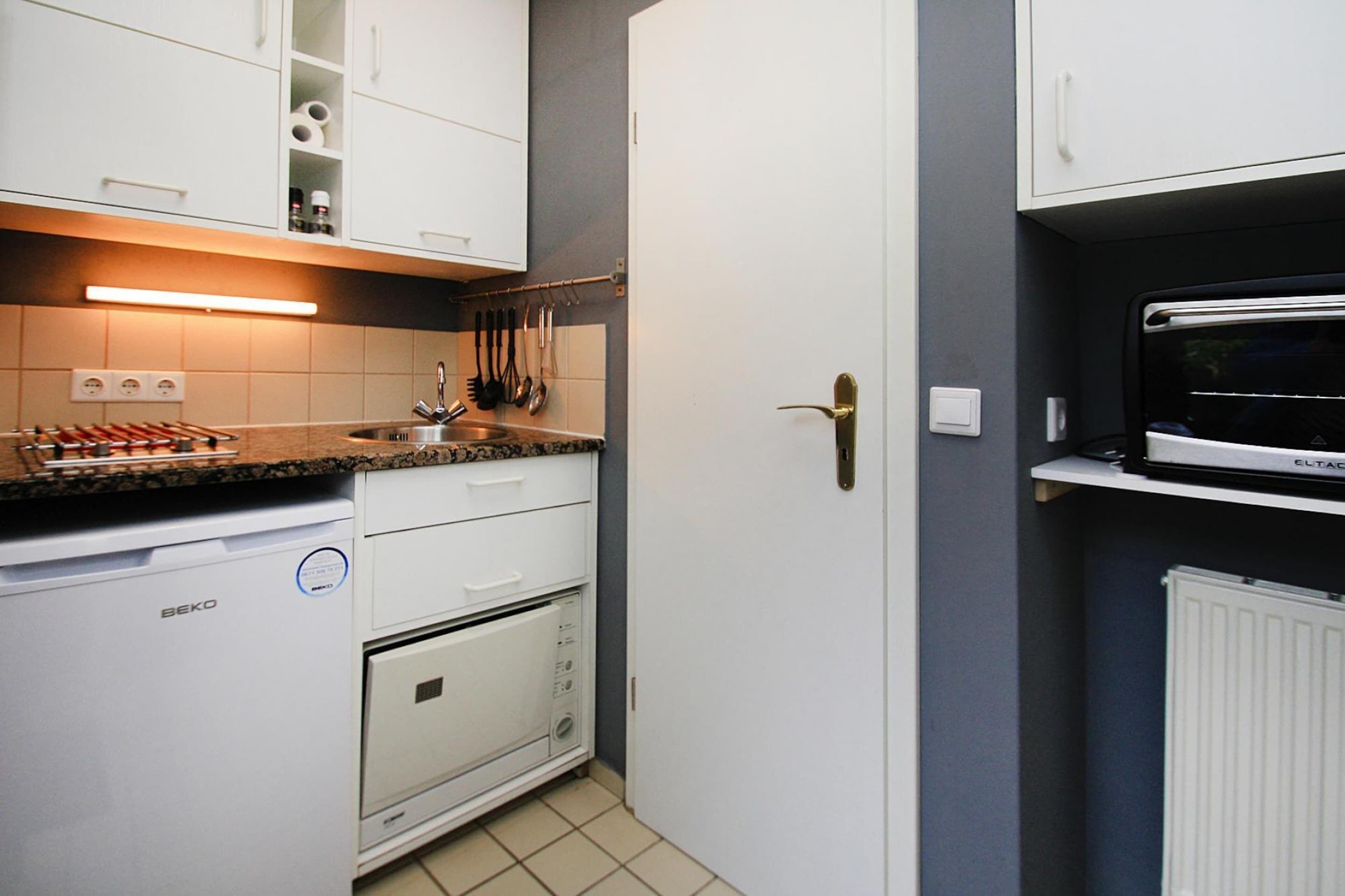 A compact kitchen with white cabinets, a built-in oven, and a microwave.