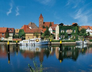 A canal with boats, historic buildings, and a church tower. - Holiday Home, Plau am See (Plau am See)