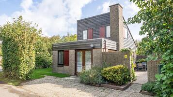 A modern two-story house with a brick facade, a sloped roof, and a gravel driveway.