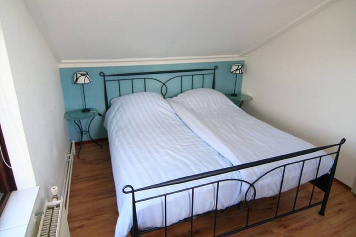 A single bed with a metal frame in a room with a sloped ceiling.