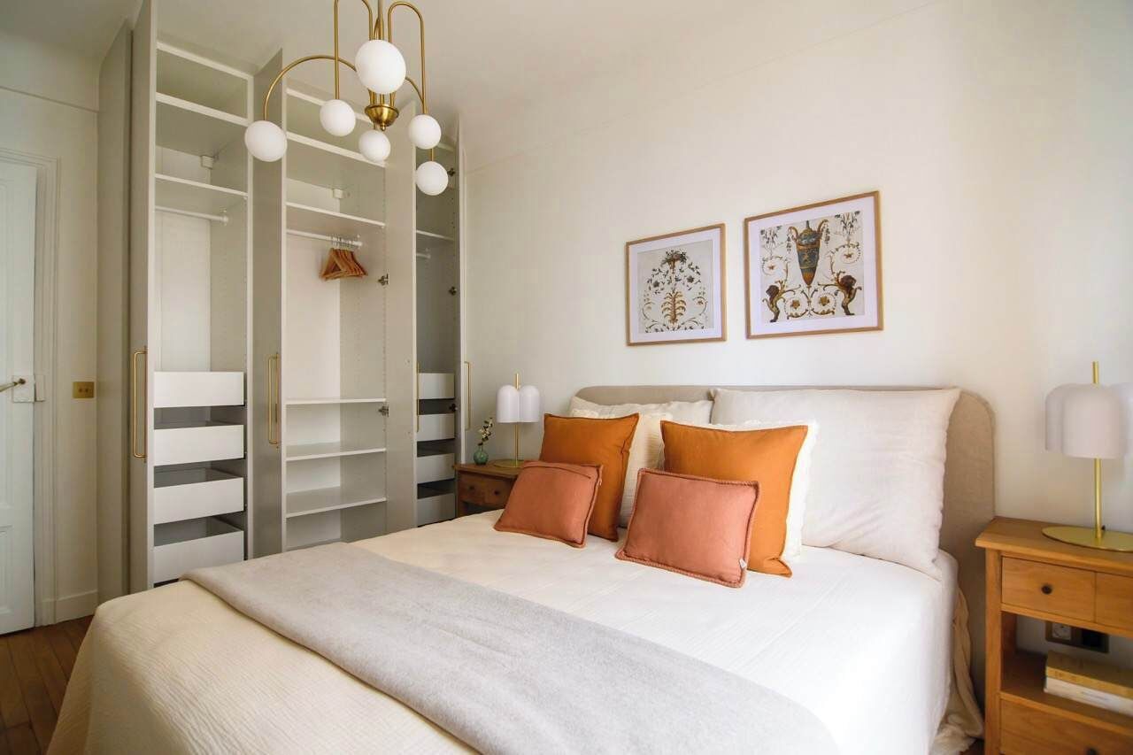Une chambre à coucher avec un lit, une armoire et deux tableaux encadrés accrochés au mur.