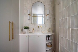 A modern bathroom with a white vanity, gold fixtures, and a large mirror.