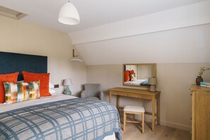 A bedroom with a bed, a desk, a chair, a mirror, and a lamp.