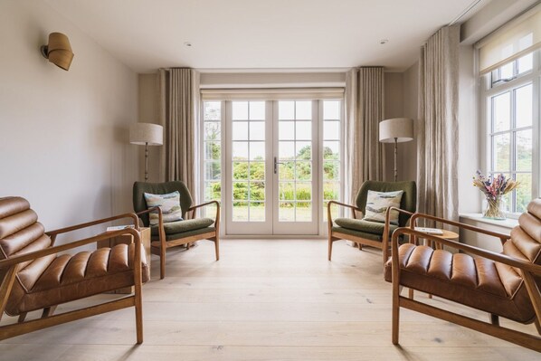 A spacious room with a large window, two leather sofas, a green armchair, and a small table.