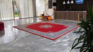 A spacious lobby with a large red carpet, a reception desk, and a TV screen. - Hotel Hariz Son (Berrechid)