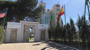 A hotel entrance with a traditional archway, a signboard, and flags. - Hotel Hariz Son (Berrechid)