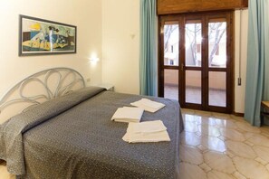 Ein Schlafzimmer mit einem Bett, einem Bild an der Wand und einer Tür, die nach draußen führt.