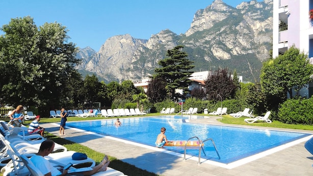 A swimming pool with lounge chairs and a mountainous backdrop.