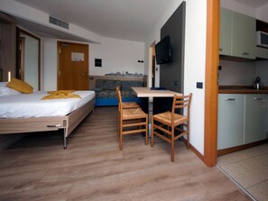 A compact room with a bed, a small desk, a chair, and a kitchenette. - Apartment in Riva del Garda (Riva del Garda)