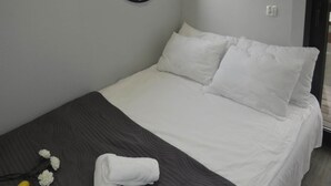 A neatly made bed with white bedding and pillows, a dark grey bedspread, and a rolled towel on the side. - Hausboat Kamien Pomorski, 20 m2, for 3 Persons on the Water (Kamien Pomorski)
