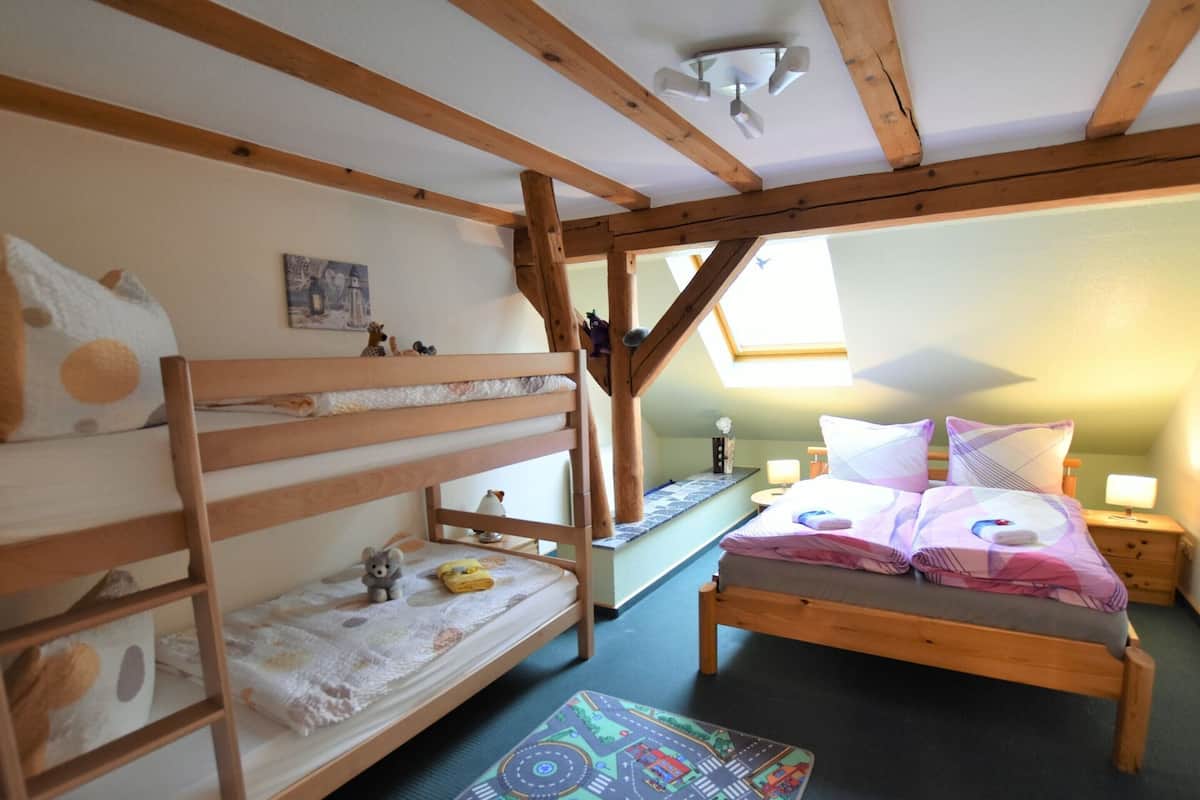 Een knus slaapkamer op zolder met een stapelbed, een éénpersoonsbed en een dakraam.