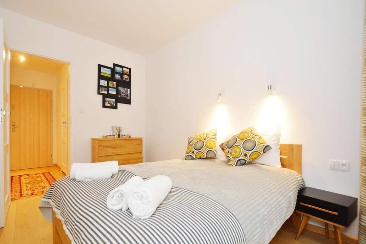 Ein Schlafzimmer mit einem Bett, Nachttischen, einer Kommode und einer an der Wand befestigten Fotocollage.