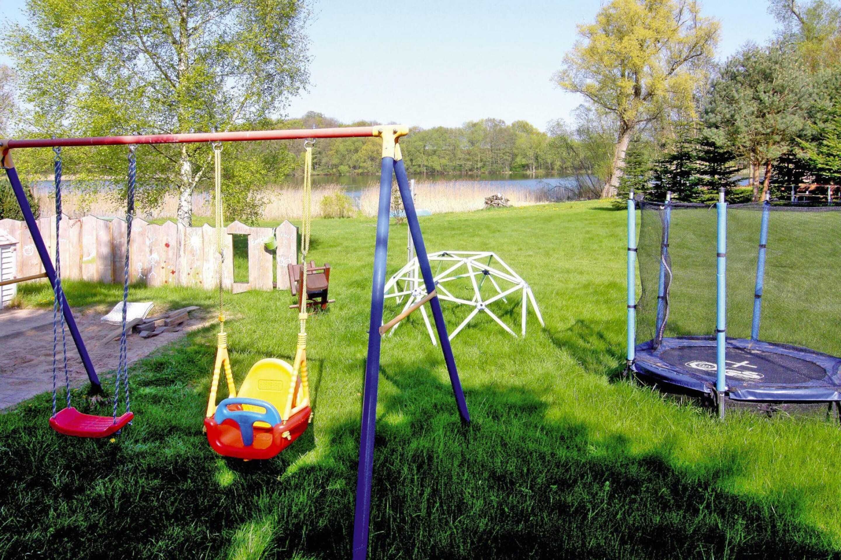 A playground with swings, a slide, and a trampoline.