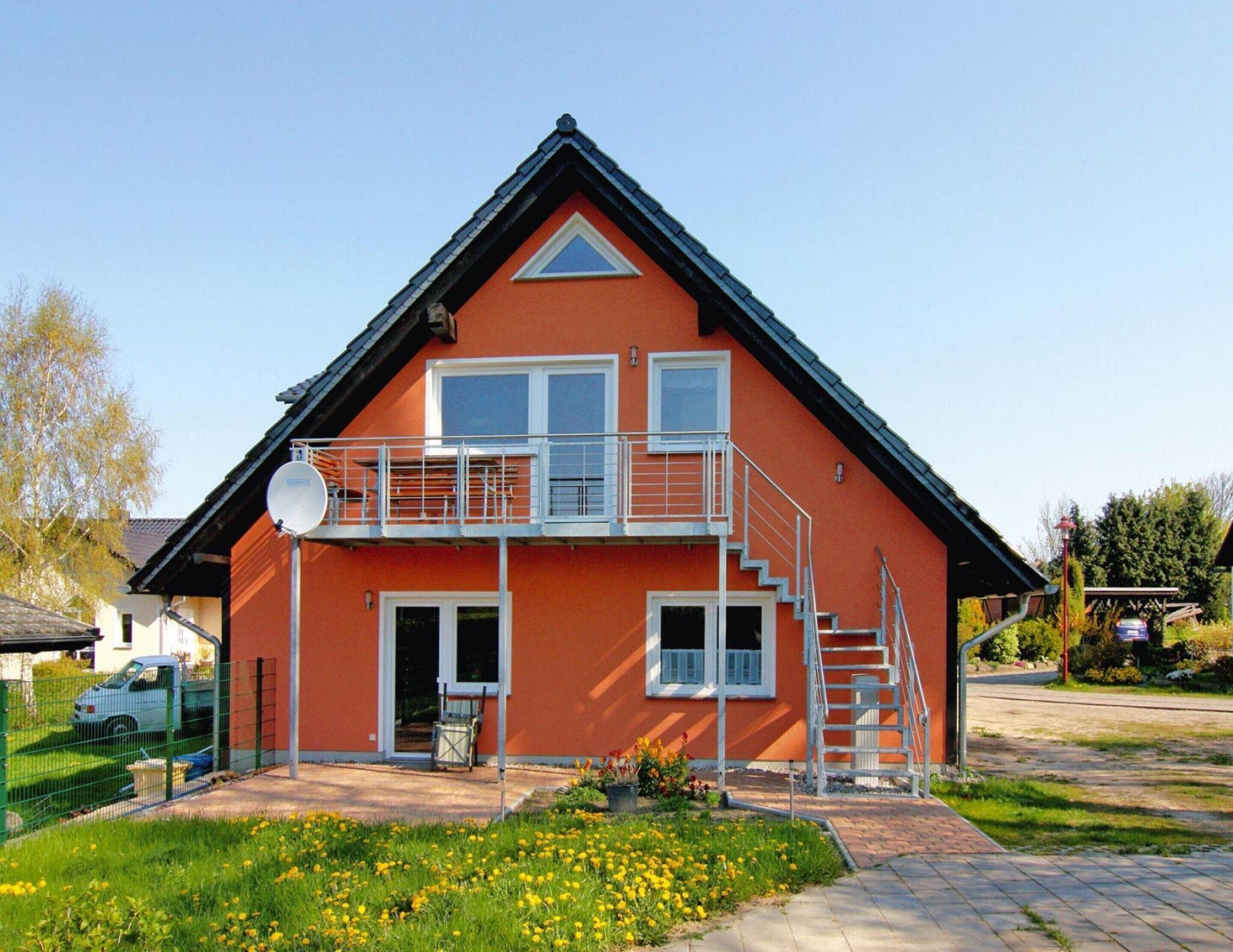 Et toetagers hus med balkon, parabolantenne og trappe op til øvre etage.