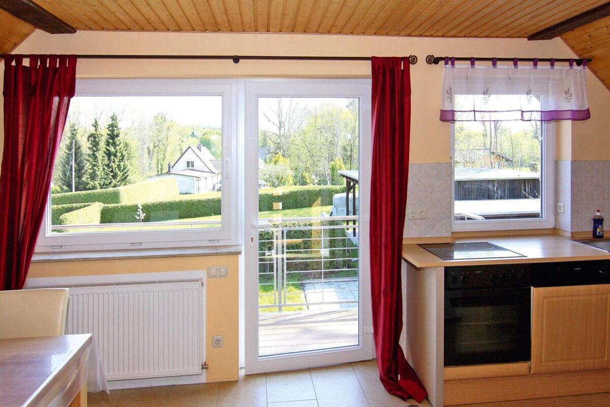 Eine Küche mit einer Schiebetür zum Balkon, einem Einbauherd und einem Geschirrspüler.
