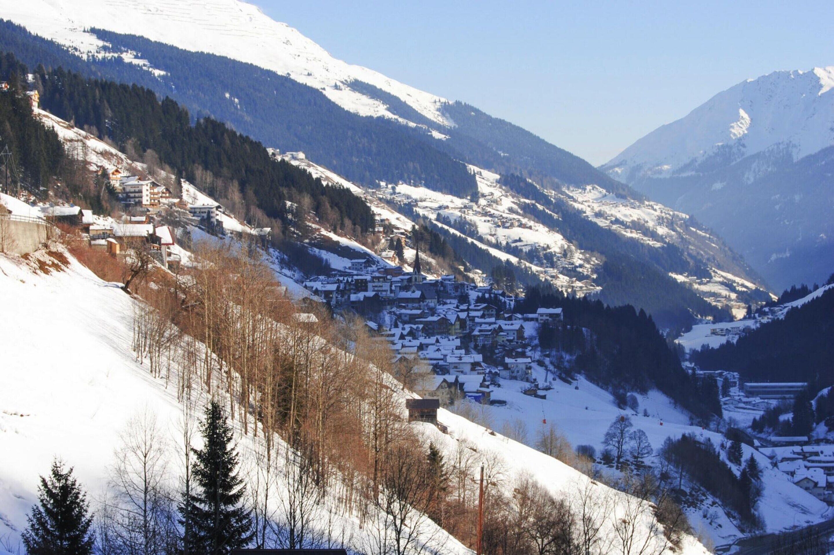Un villaggio montano innevato con edifici immersi nella valle.