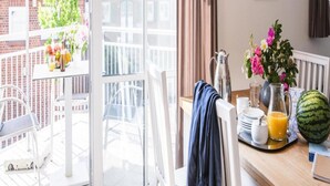 A balcony with a table set for breakfast, a chair, a hanging towel, and a view of the cityscape. - Apartment, Zingst (Zingst)