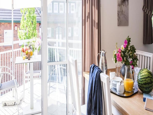 Un balcón con una mesa preparada para el desayuno, una silla, una toalla colgando y vistas de la ciudad.