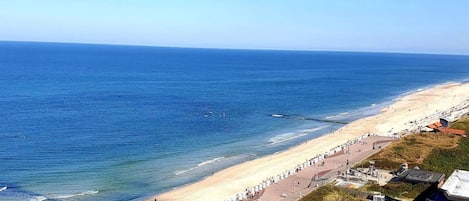 A coastal beach with a promenade, buildings, and a clear view of the ocean.