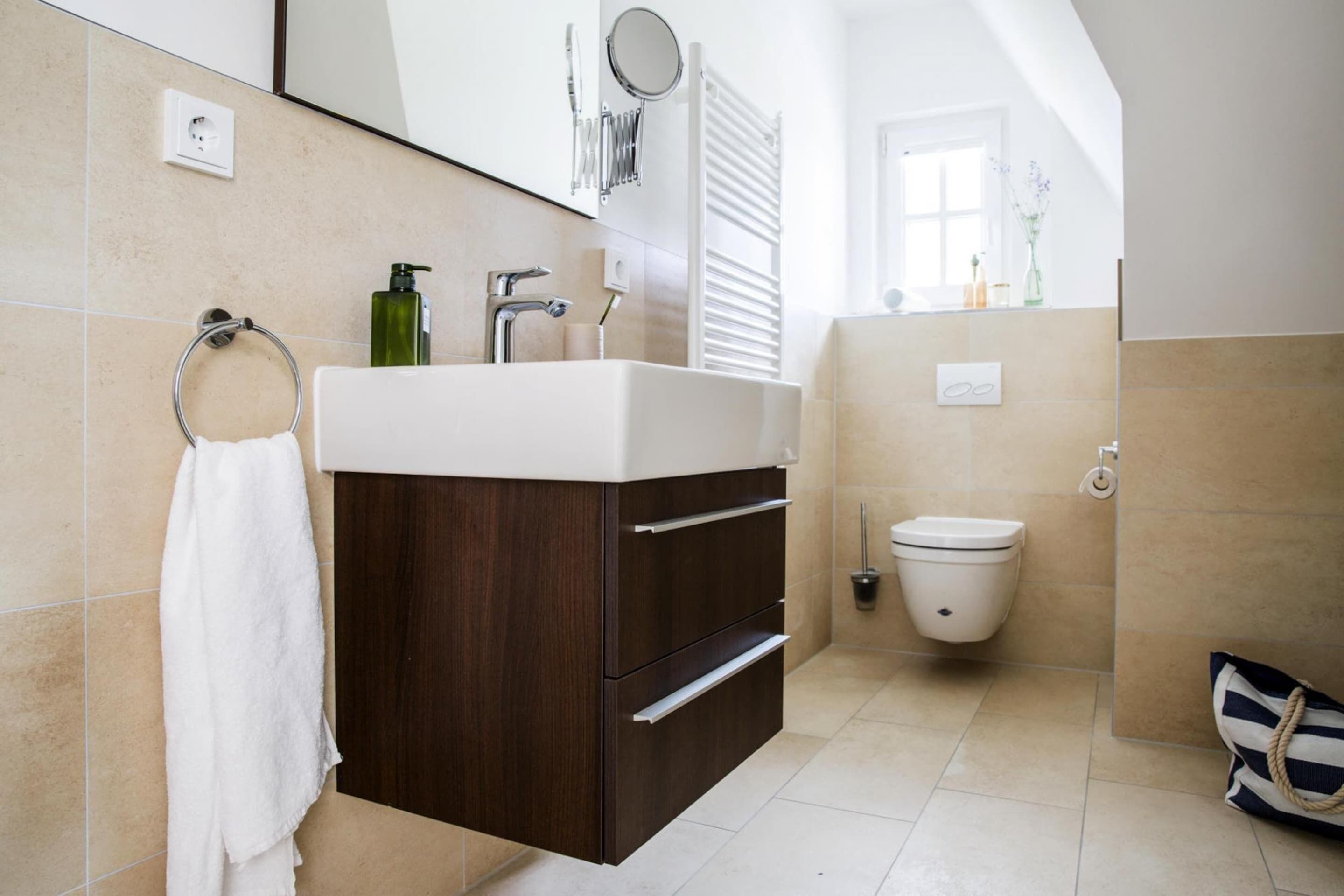 A modern bathroom with a vanity, toilet, and a towel rack.