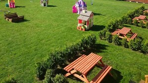 A well-maintained grassy area with picnic tables, small playhouses, and a clear sky. - Cozy Holiday Homes Near the Beach in Jaroslawiec (Postomino)