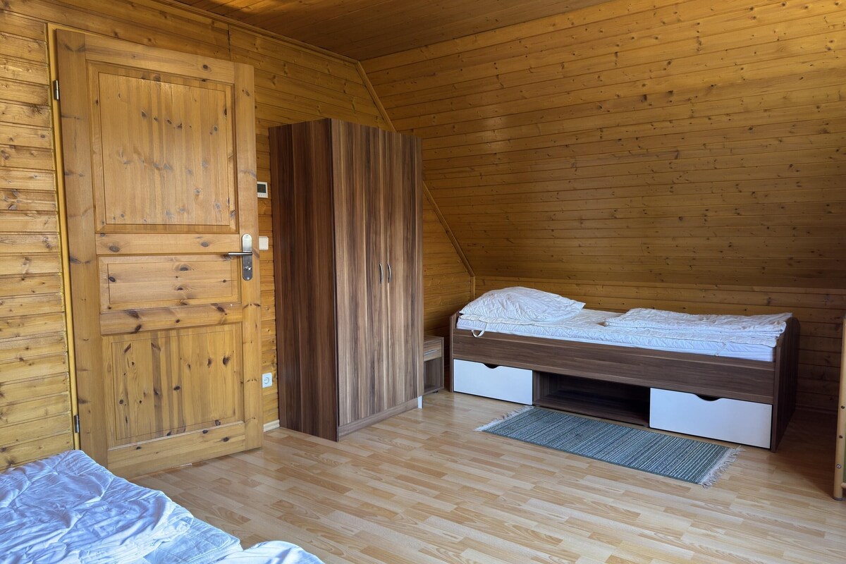A wooden cabin bedroom with a bed, a wardrobe, and a door.