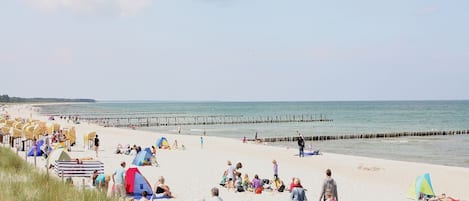 A beach with people, tents, and a pier.