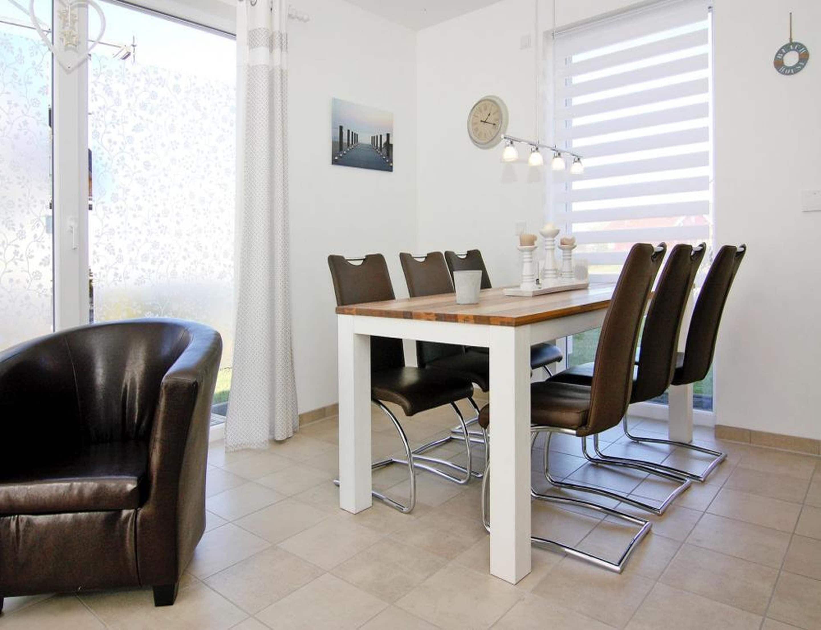 A dining area with a white table, brown chairs, and a clock on the wall.