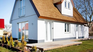 A modern two-story house with a thatched roof, large windows, and a wooden deck. - House, Boiensdorf (Boiensdorf)
