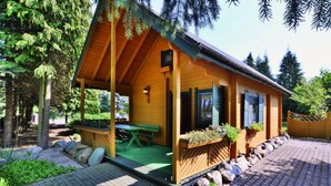 Une cabane en bois avec une véranda, une table de pique-nique et un chemin pavé de pierres.