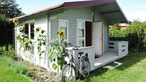 Une petite maison à un étage, dotée d’un porche, d’un vélo et de tournesols dans le jardin.