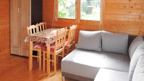 L’intérieur d’un chalet en bois comprend une table à manger, des chaises, un canapé et une armoire.