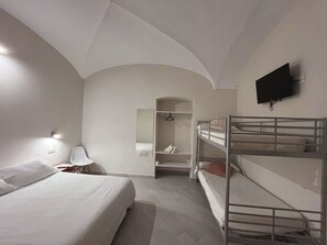 Une chambre avec des lits superposés, un téléviseur à écran plat, un miroir et un dressing.