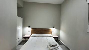 Un hotel con una decoración minimalista, con una cama grande, dos mesitas de noche y un cabecero de madera.