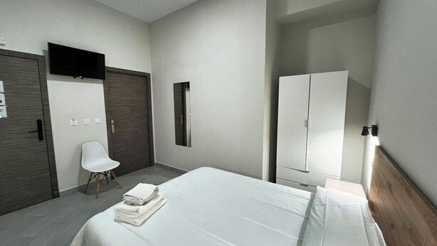 A modern hotel room with a large bed, a wardrobe, a chair, and a mirror. - Hostal Pompeya (Merida)