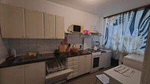Une cuisine de taille réduite avec des meubles blancs, un four à micro-ondes, une cuisinière et un évier.