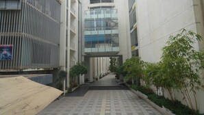 Un couloir au sol carrelé, bordé de bâtiments modernes et agrémenté de plantes en pot.