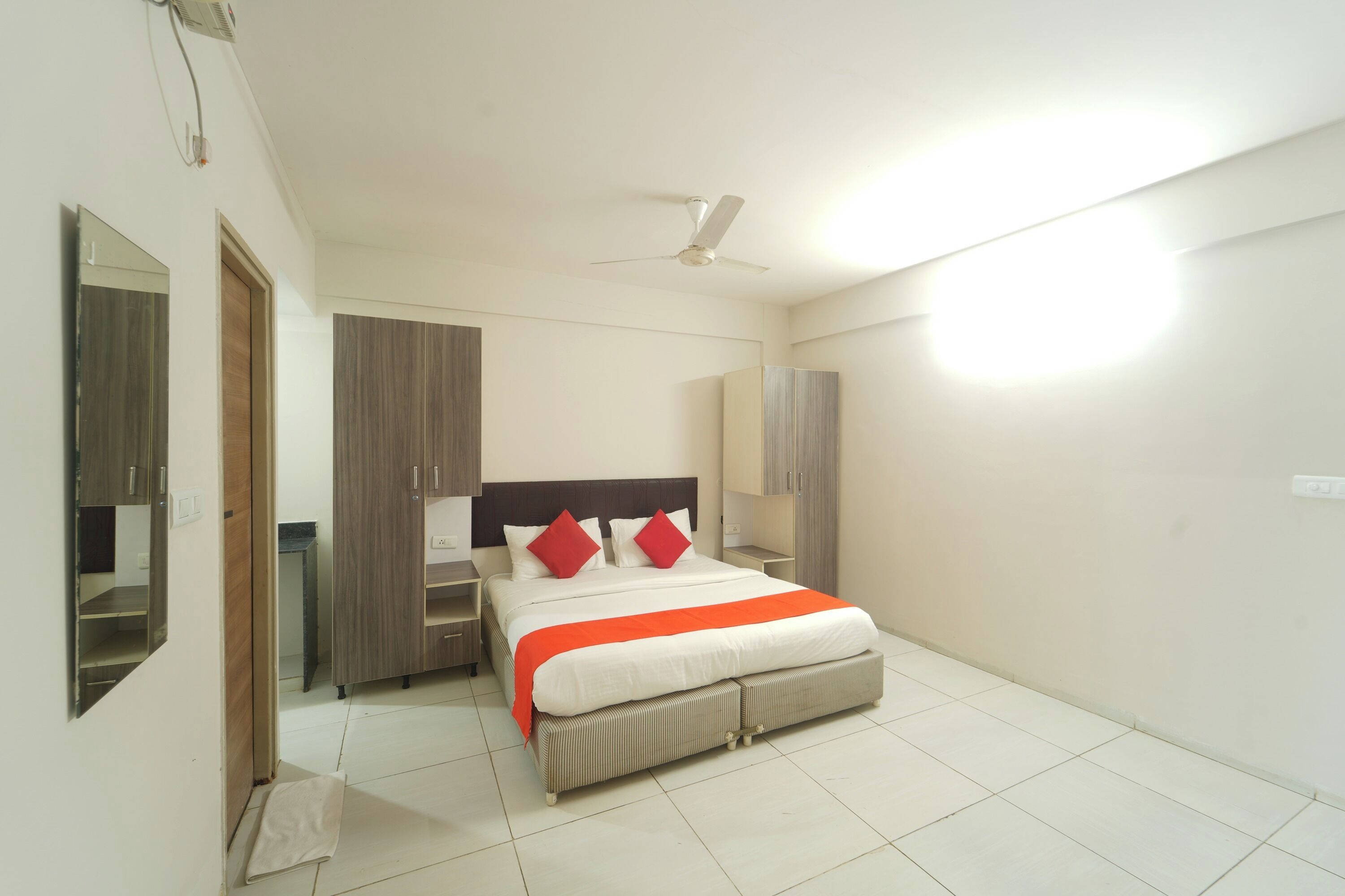 A bedroom with a bed, nightstands, a wardrobe, a mirror, and a ceiling fan.