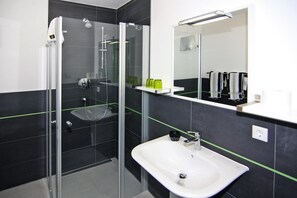 A modern bathroom with a glass-enclosed shower, a white sink, and a mirror above it. - Apartment House Calmsailing, Borgerende (Boergerende-Rethwisch)