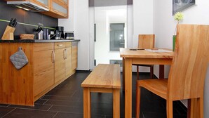 A modern kitchen with wooden cabinets, a black countertop, and a wooden dining table with chairs. - Apartment House Calmsailing, Borgerende (Boergerende-Rethwisch)