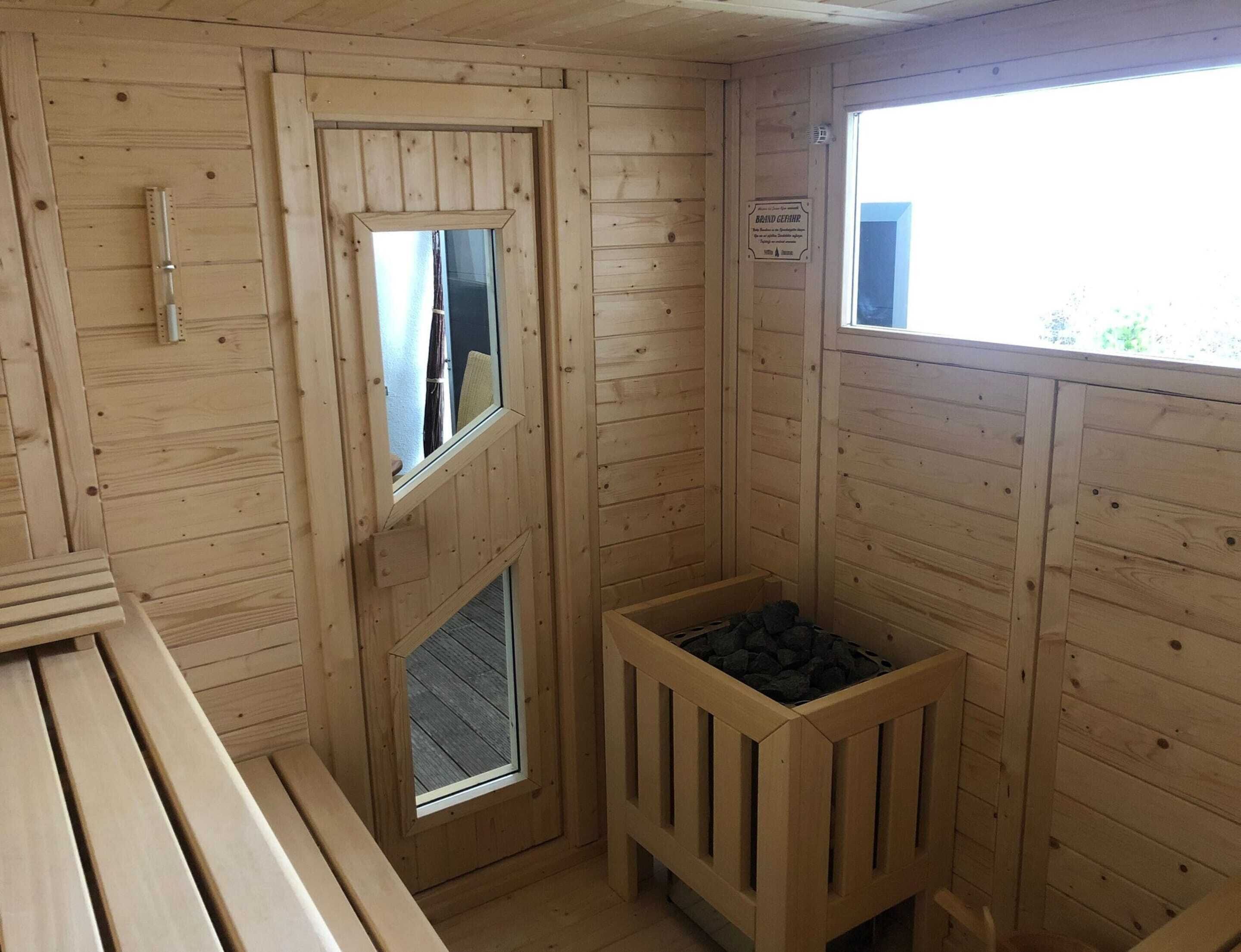 A sauna room with wooden walls, a bench, a window, and a wooden bench with a metal frame.
