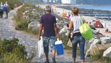 A cobblestone path leading to a beach with people walking and beachgoers in the background.