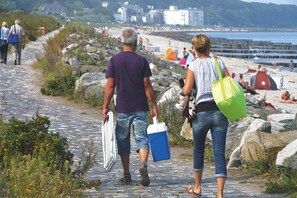A cobblestone path leading to a beach with people walking and beachgoers in the background. - Apartment House Calmsailing, Borgerende (Boergerende-Rethwisch)