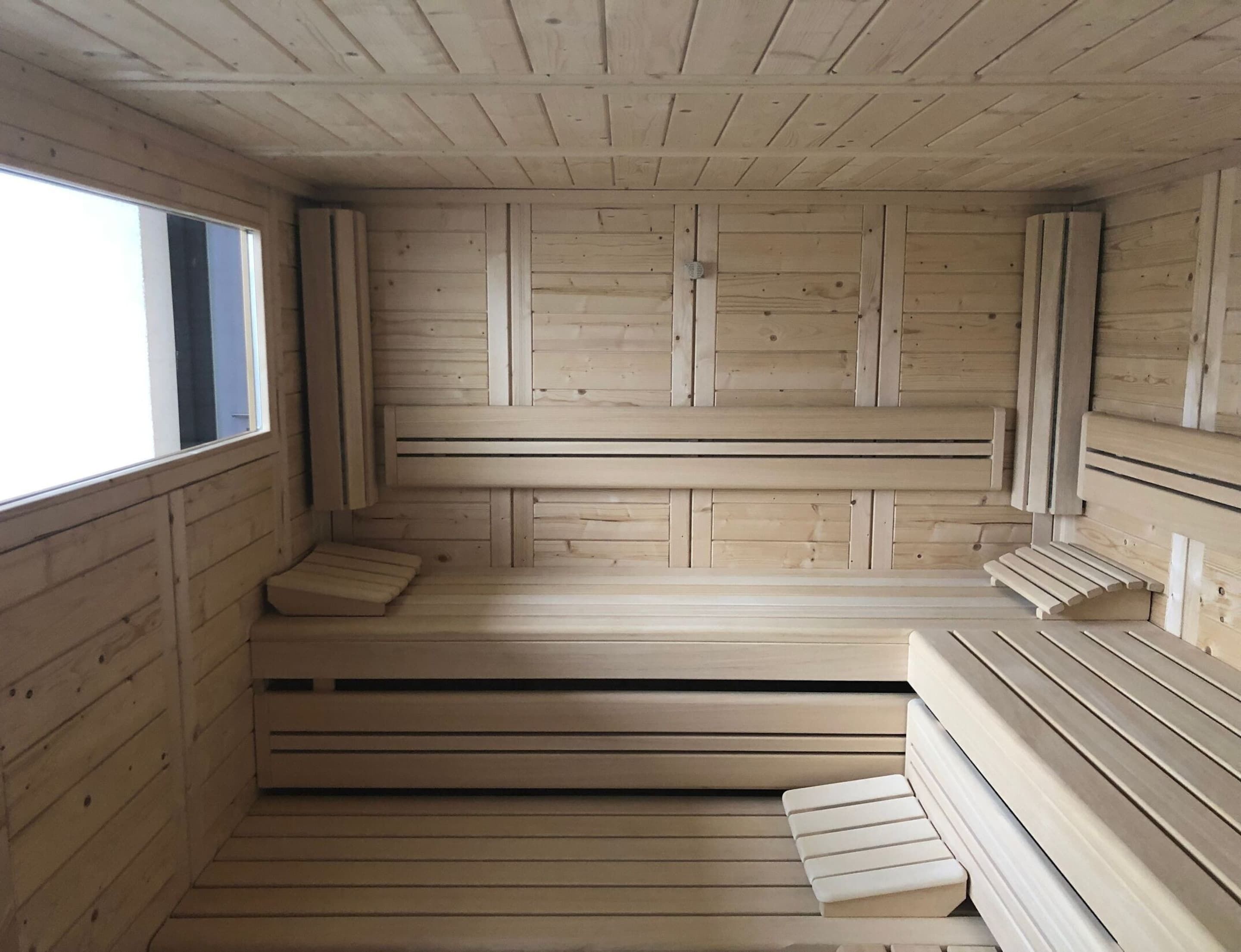 Un sauna con bancos de madera y un ventanal grande.