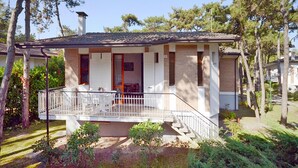 A two-story house with a covered porch, a small garden, and a staircase leading to the upper floor.