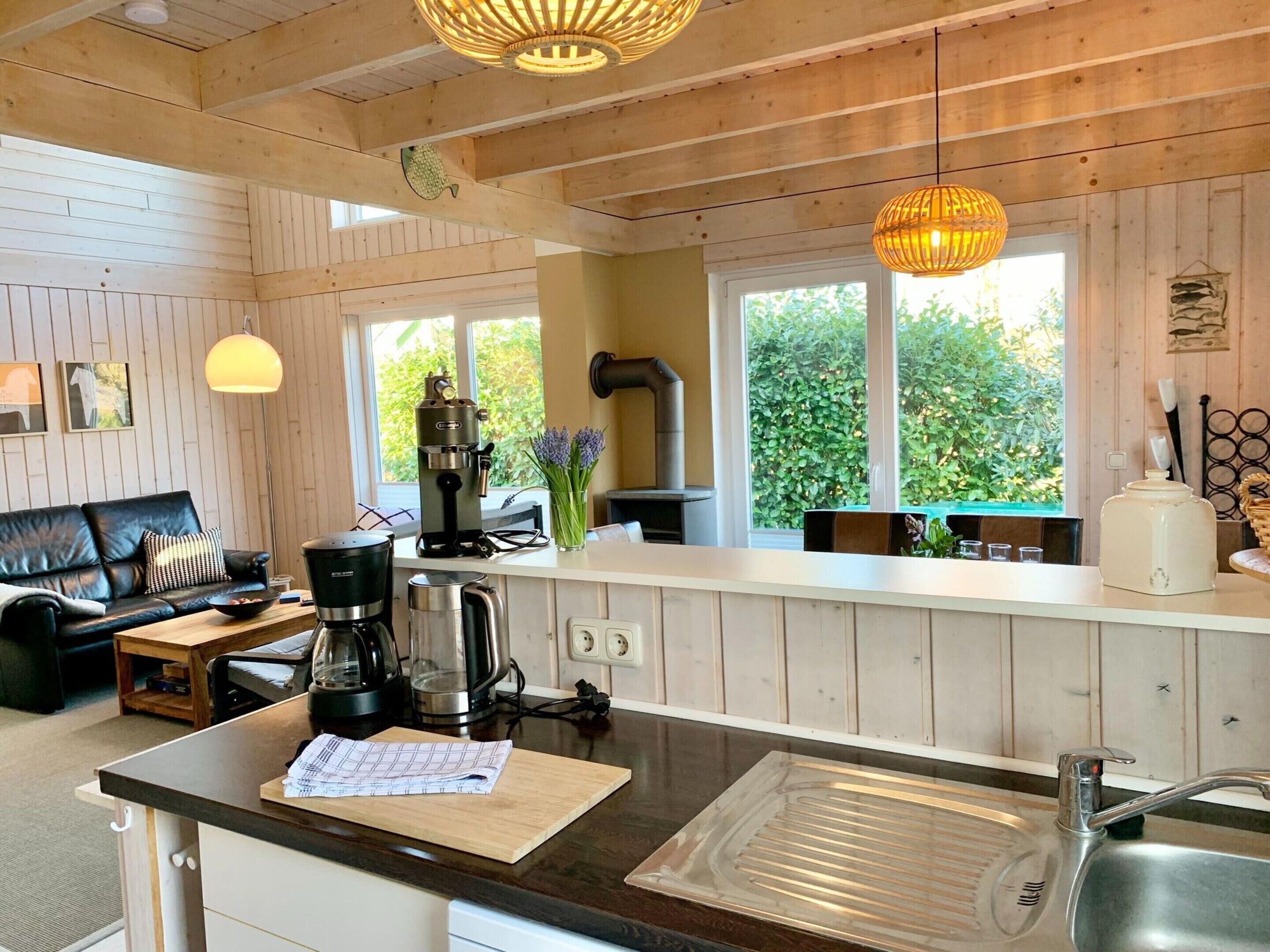 A cozy kitchen with a coffee machine, kettle, and a dining area with a sofa and table.