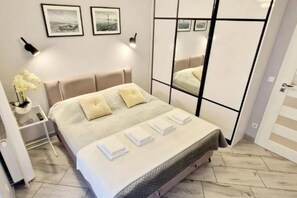 A neatly arranged bedroom with a bed, bedside tables, and a mirror. - Apartment With a Terrace in Mielno (Mielno)