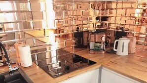 A kitchen with a modern design, featuring a built-in stove, a coffee maker, and a kettle. - Apartment With a Terrace in Mielno (Mielno)