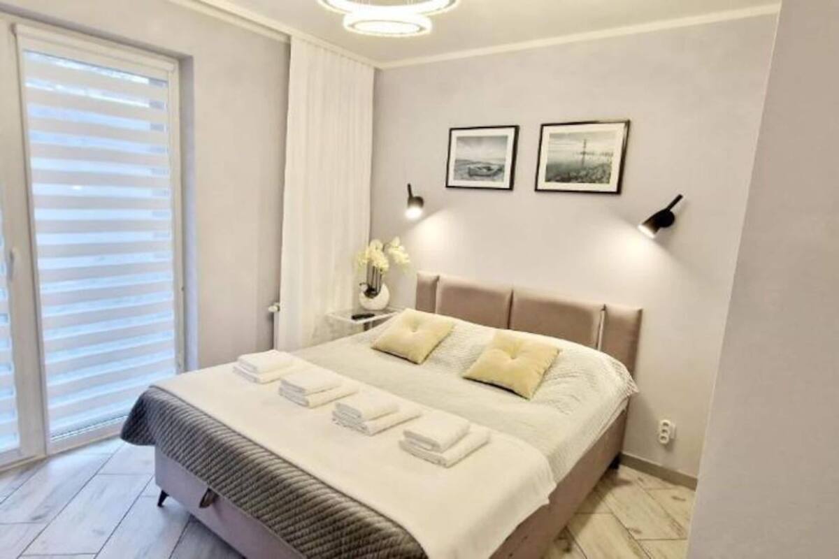 A modern bedroom with a bed, bedside lamps, and two framed pictures on the wall.