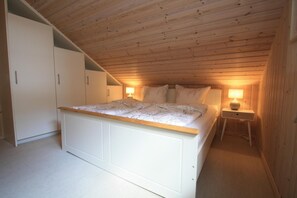 A bedroom with a wooden ceiling, a bed with a white headboard, two bedside lamps, and a wardrobe. - Holiday Home Seeidyll am Dummer See, Dummer (Dummer)